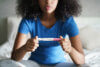 Teenage girl sitting on bed reading pregnancy test result