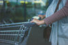 A pregnant young woman is pushing a shopping trolley outside a supermarket