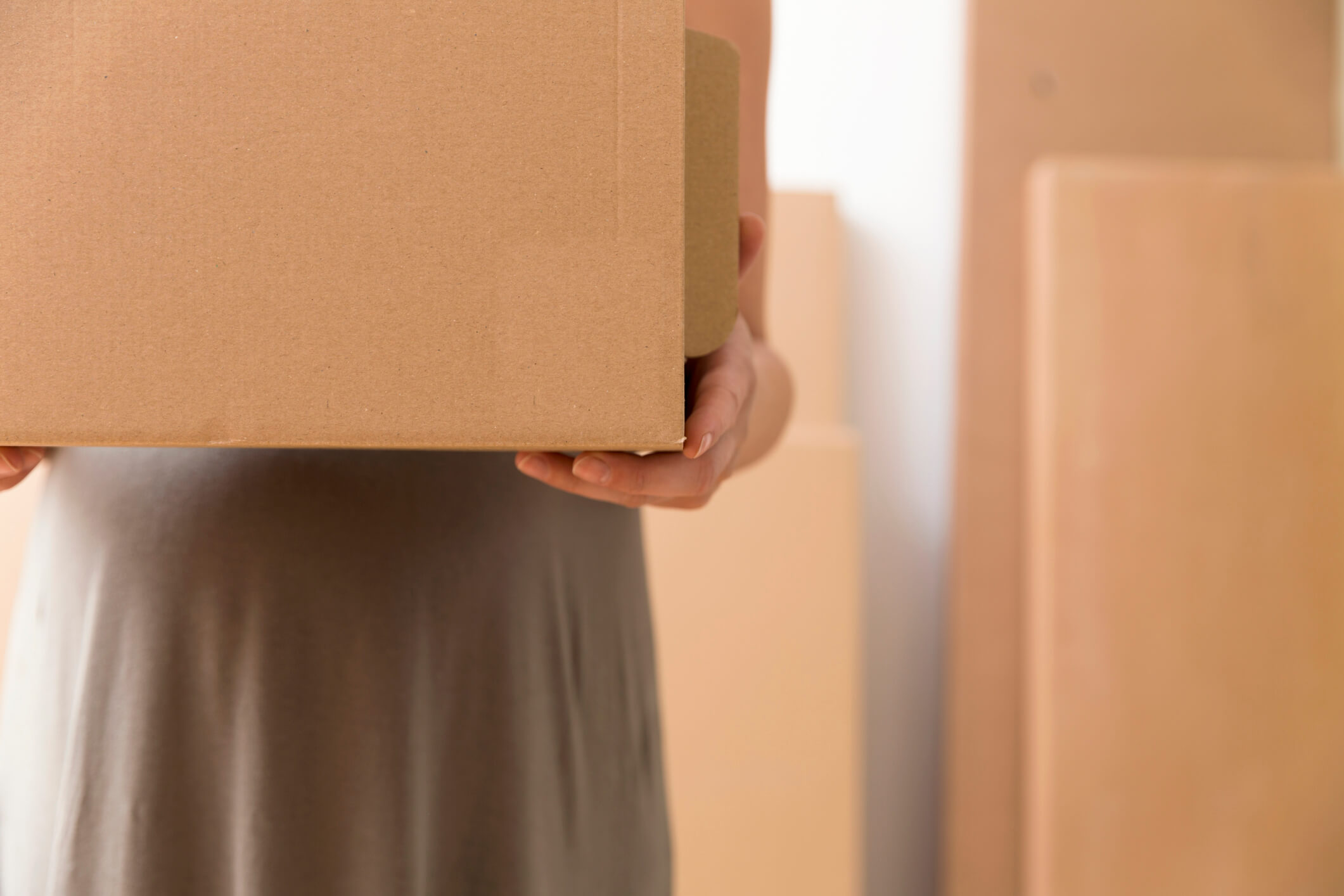 Relocation and moving concept. Pregnant woman is holding cardboard box