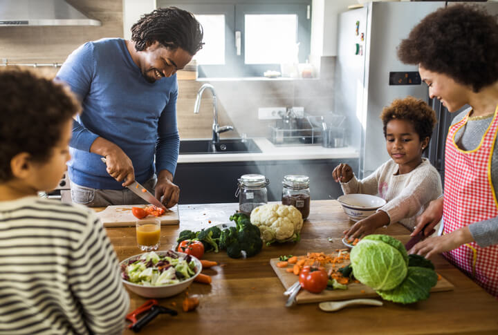 Happy black family preparing meal in the kitchen.