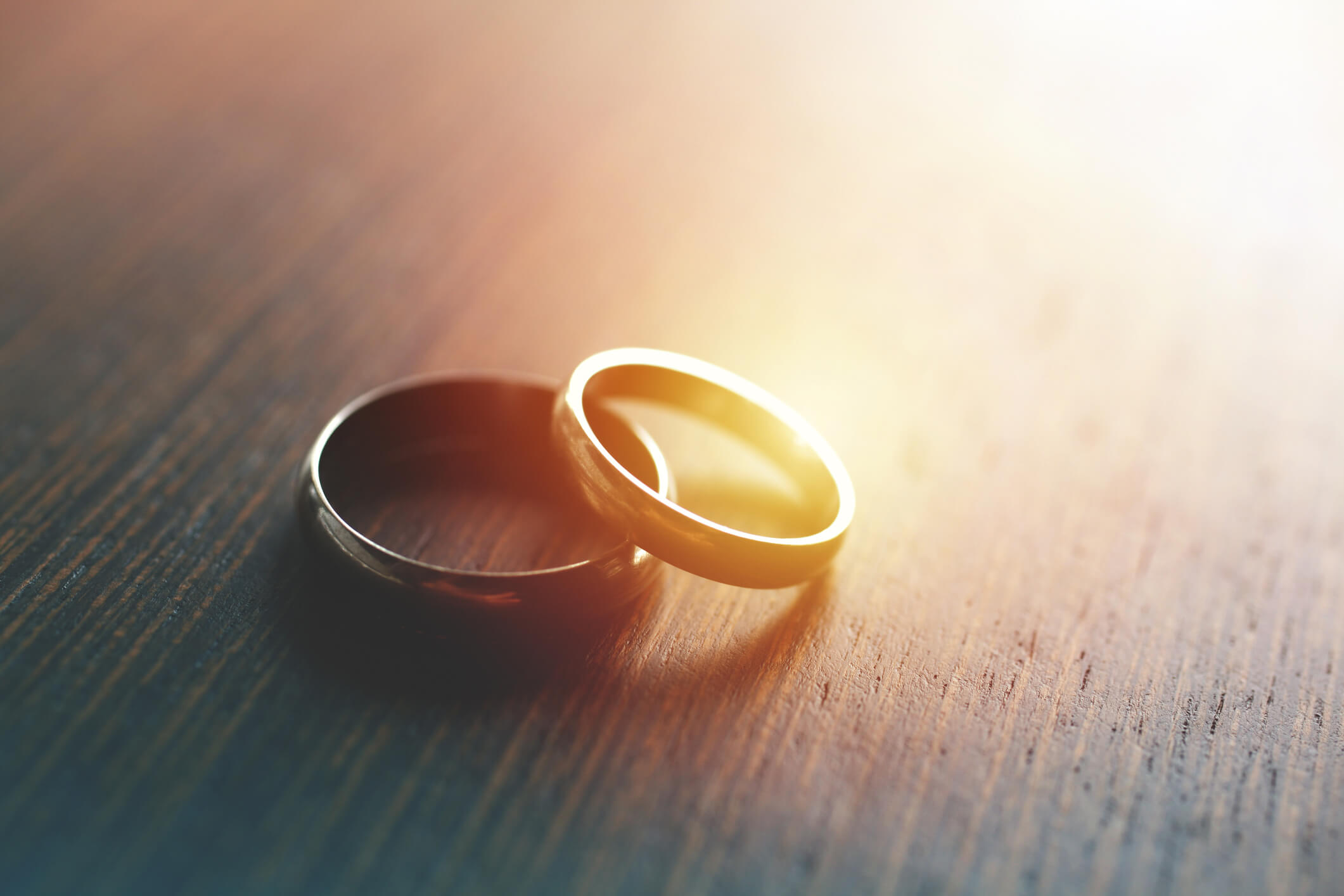 Close-up of wedding rings on table with sunlight.