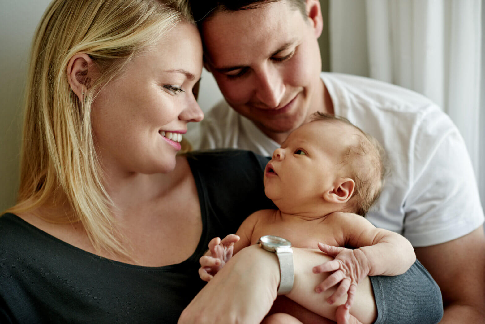 Young parents holding a baby, smiling